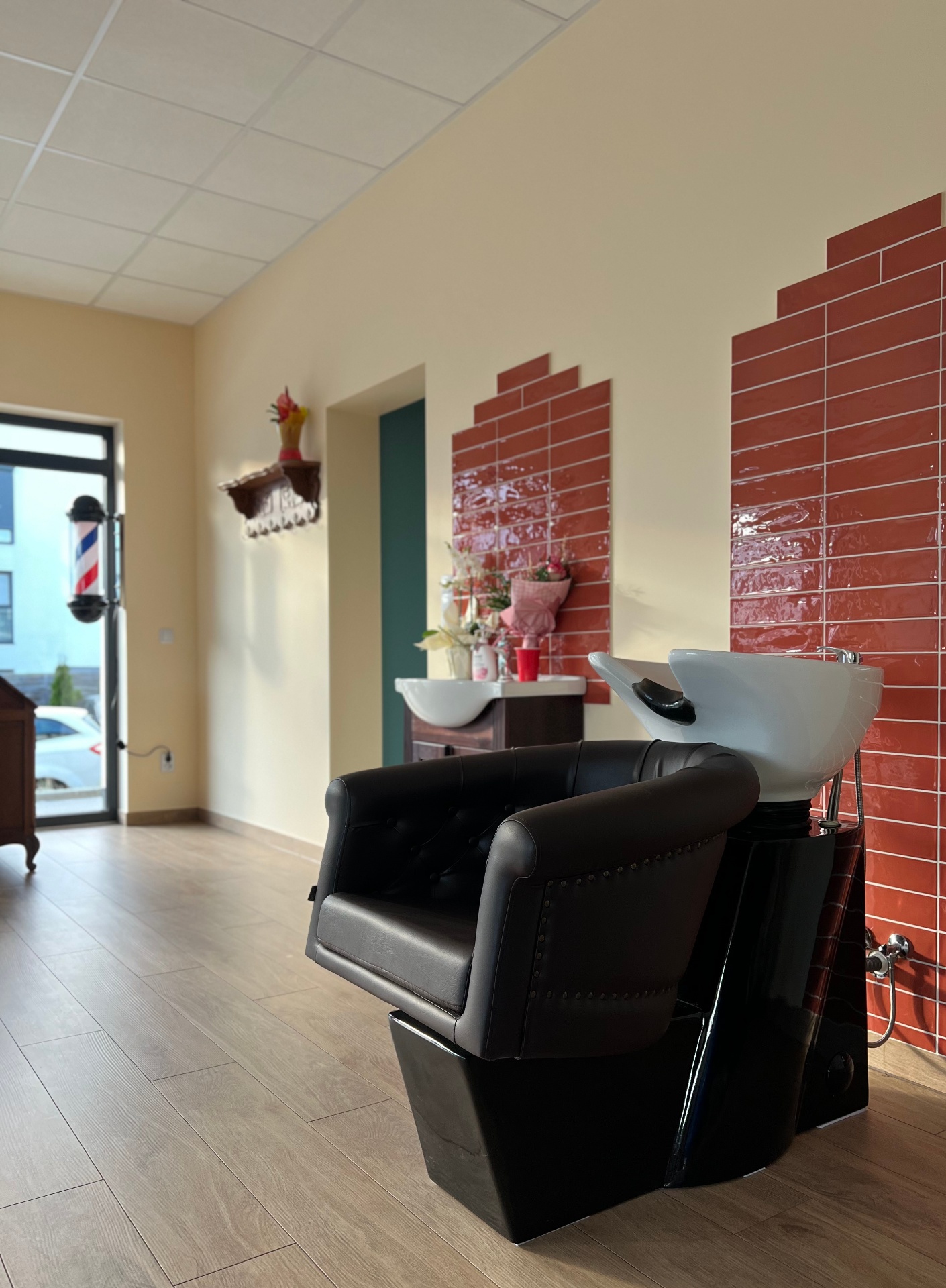 Myjnia z ceglaną ścianą w odcieniu terakoty i czarnym fotelem skórzanym